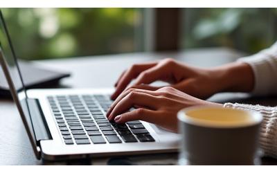 A close-up of hands typing on a laptop with a cup of coffee nearby, representing event planning.