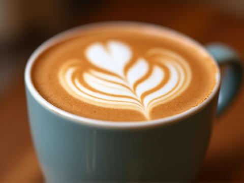 Close-up of a beautifully crafted vegan latte with intricate latte art, highlighting creamy texture and skilled preparation.